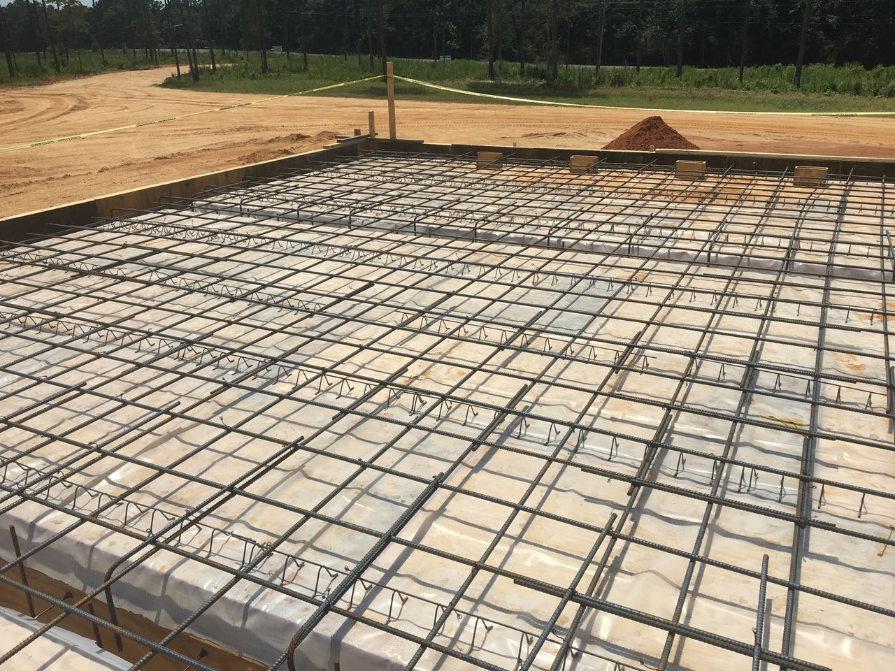 A concrete foundation is being built on a dirt field.