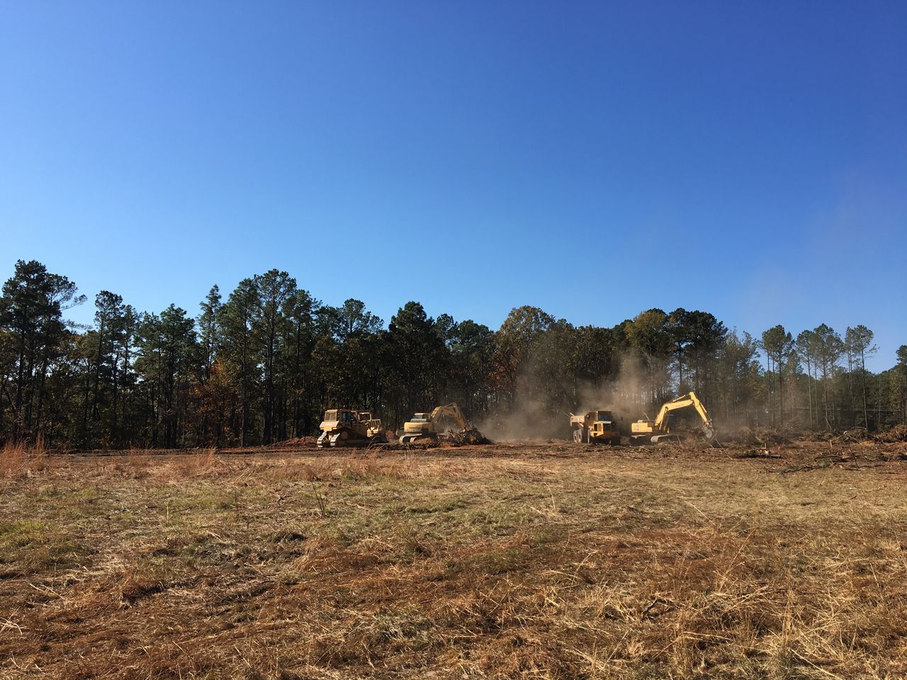 A group of construction vehicles are working in a field.