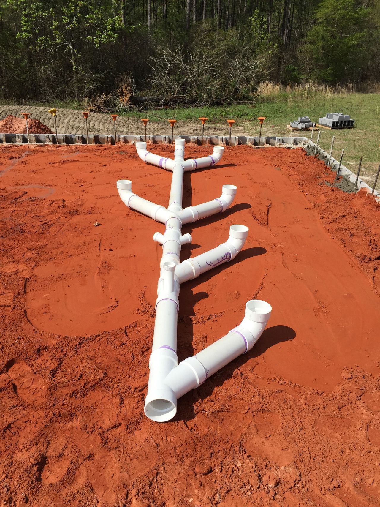 A row of white pipes sitting on top of a pile of dirt.