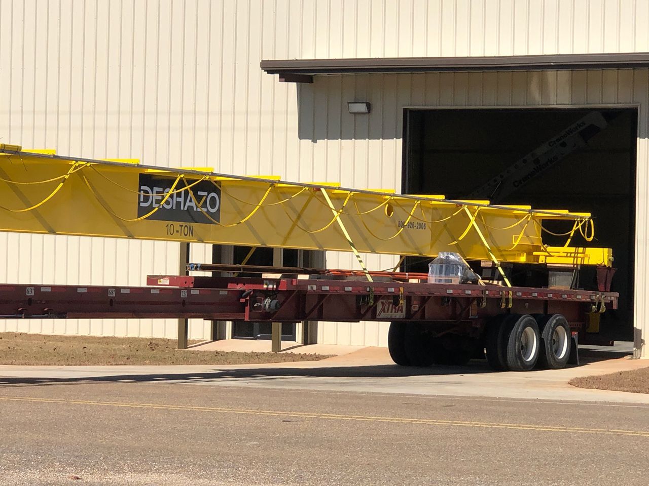 A large yellow crane is being loaded onto a trailer