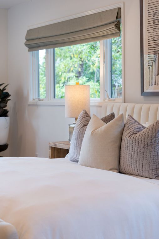A bedroom with a bed , lamp , and window.