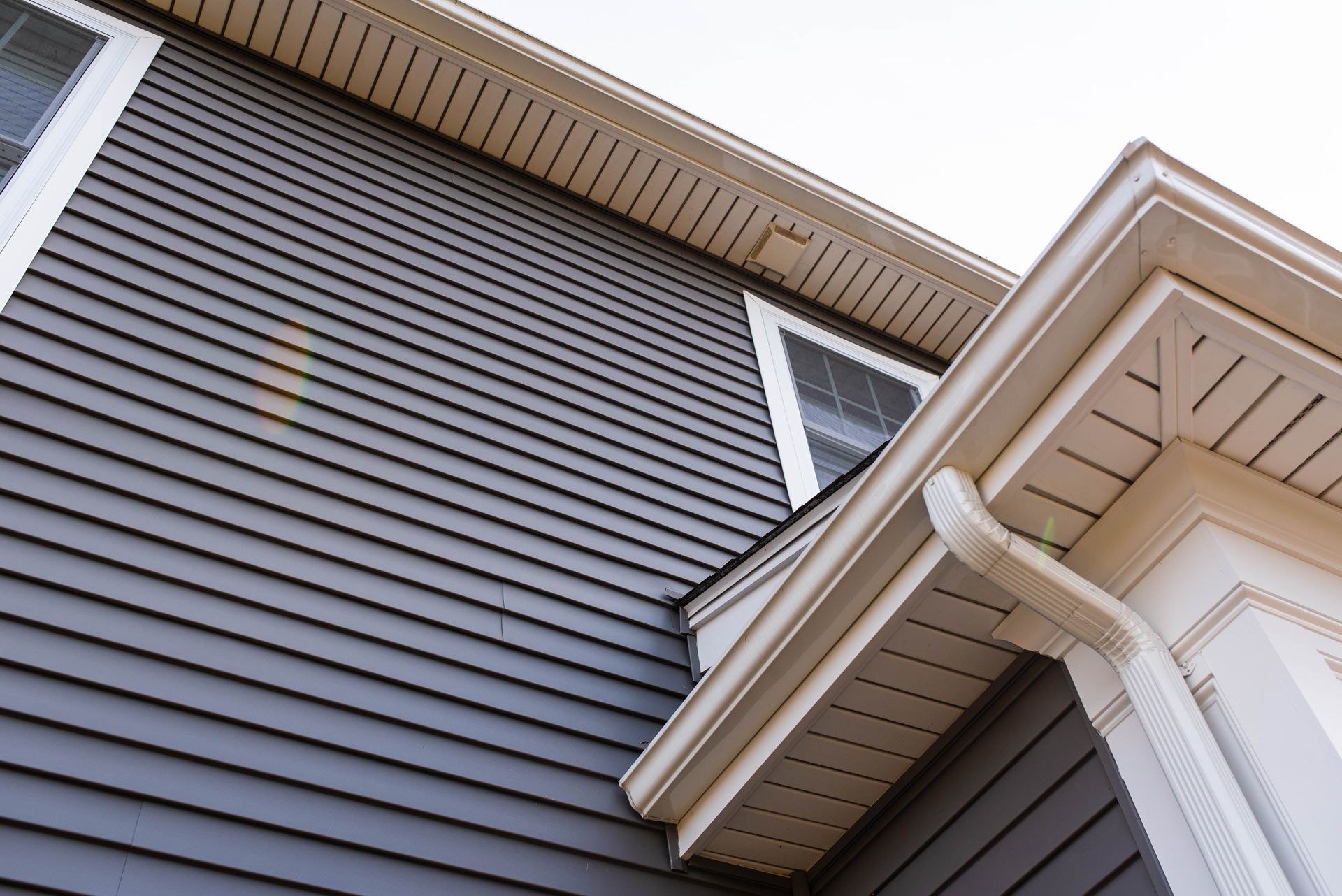 Looking up at the roof of a house with siding and gutters