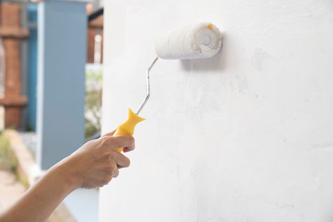 A person is painting a wall with a paint roller