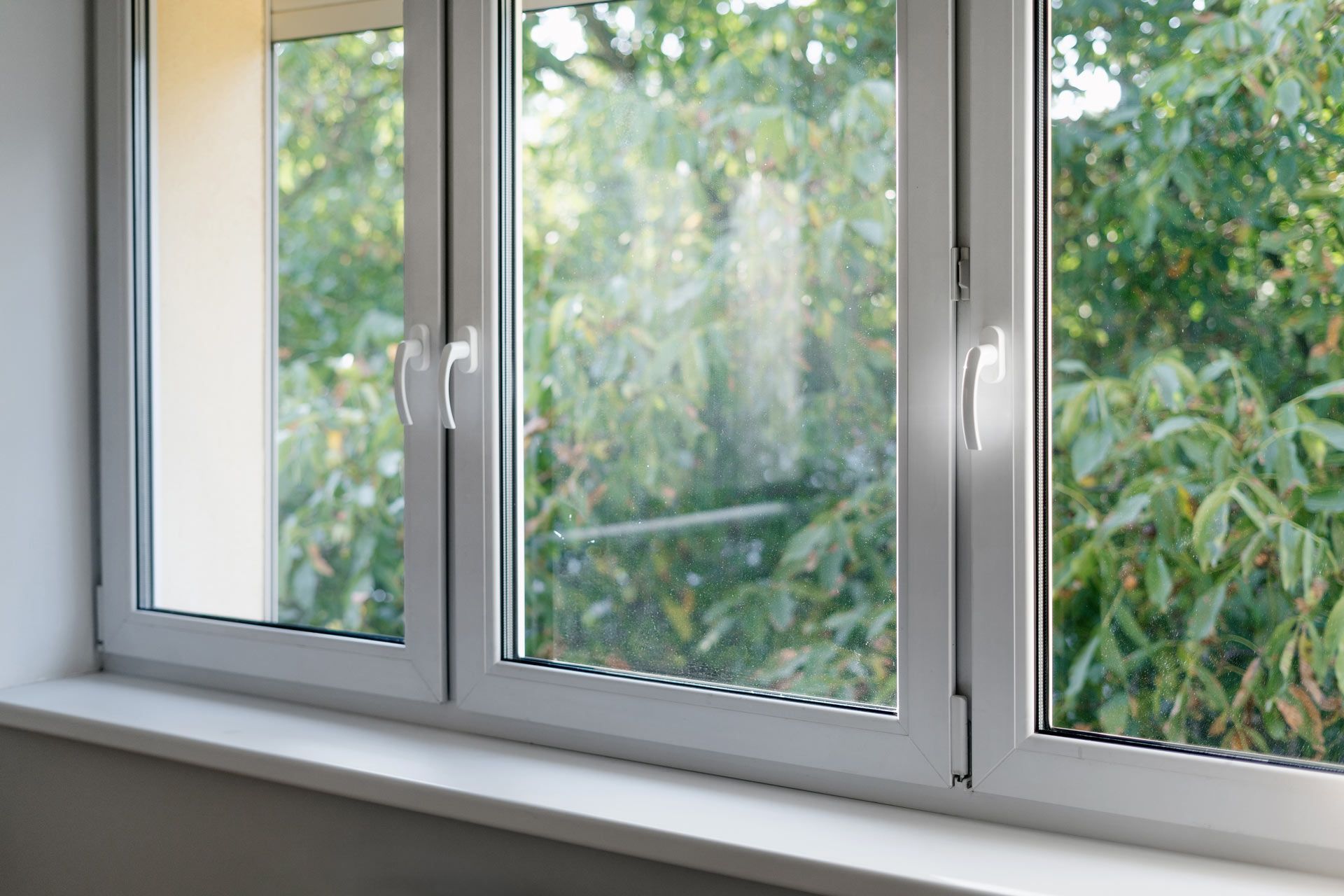 A white window with a view of trees in a room