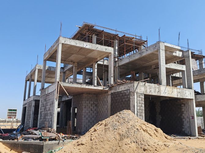 A large building under construction with a pile of dirt in front of it