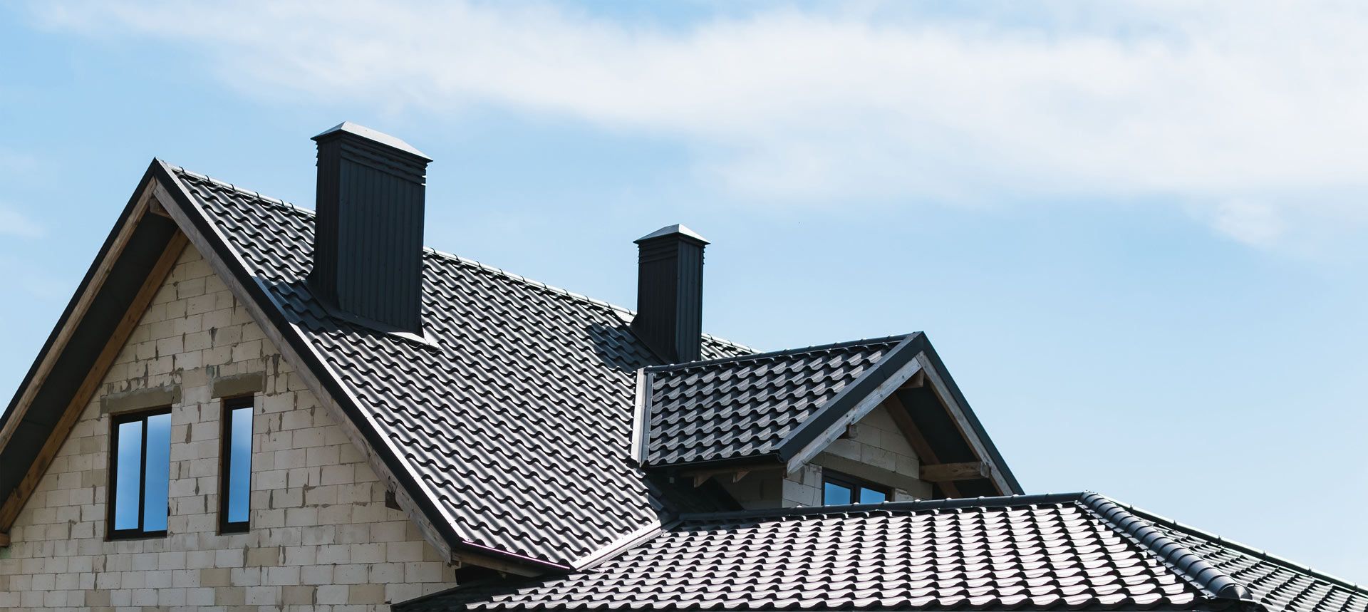 A house with a tiled roof and chimneys against a blue sky
