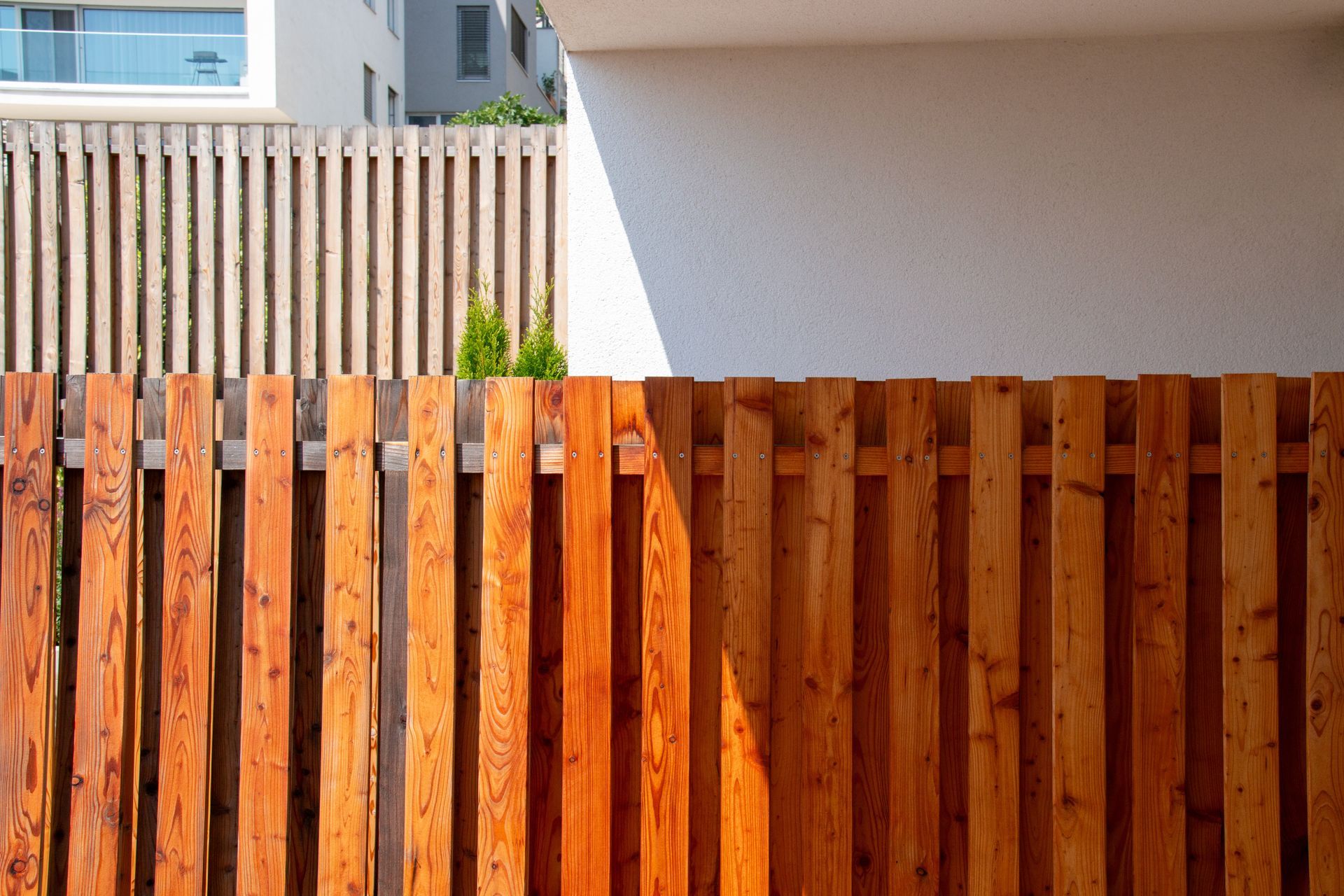 Wooden fence in front of a modern white building under bright sunlight Wooden fence in front of a modern white building under bright sunlight
