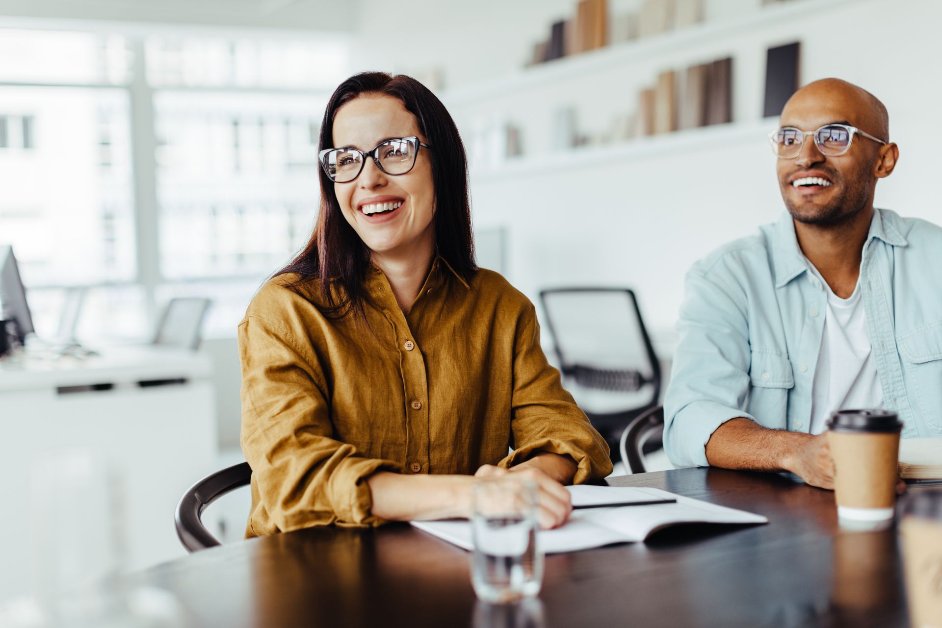 A man and a woman are sitting at a table in an office.