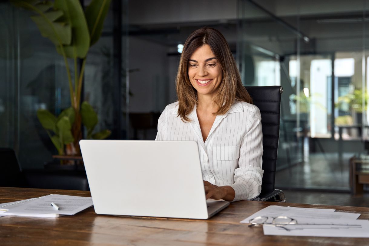 A woman is sitting at a desk using a laptop computer.