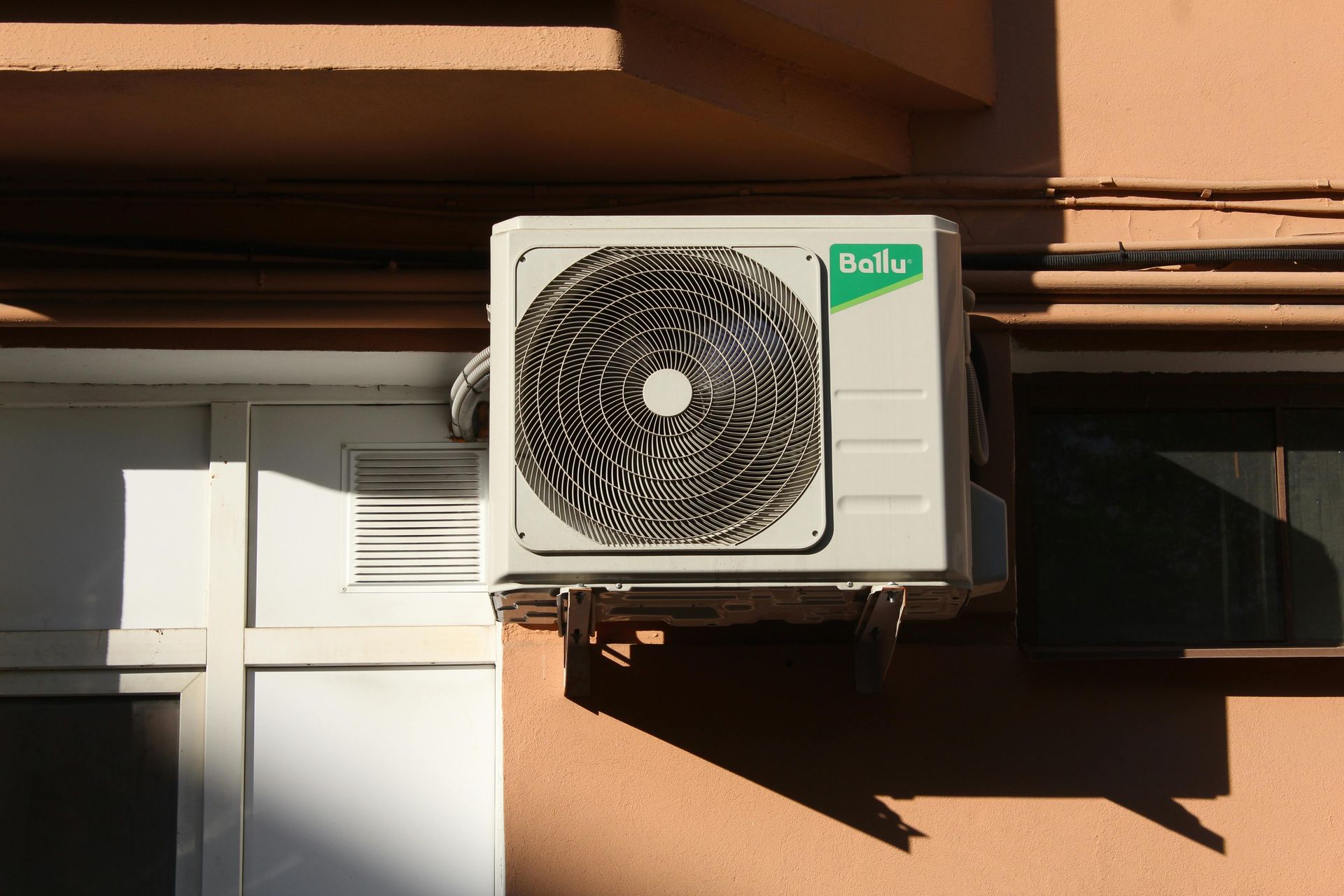 A white air conditioner is mounted on the side of a building.