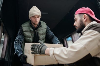 A man is giving a box to another man in a van.