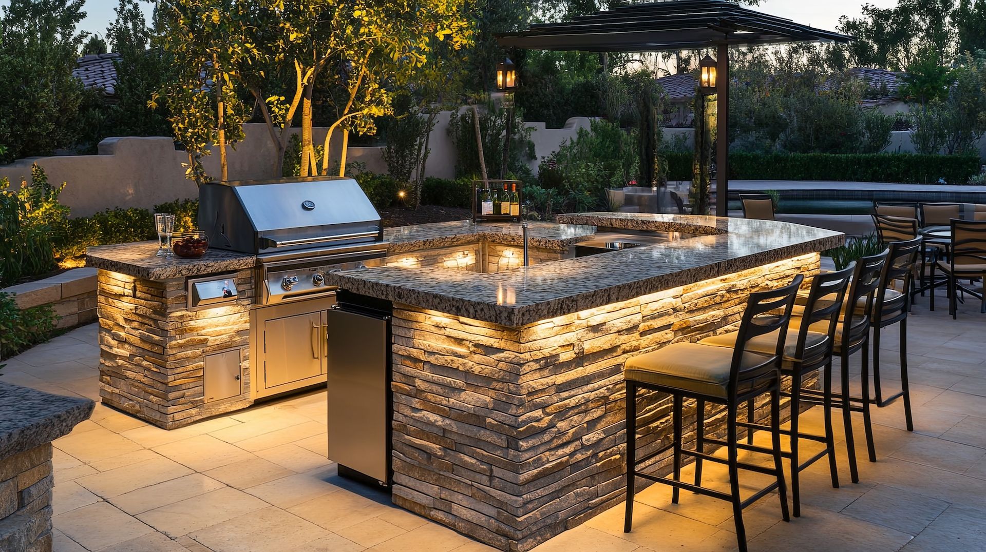 Outdoor kitchen with granite countertops, grill, bar seating, and ambient lighting.