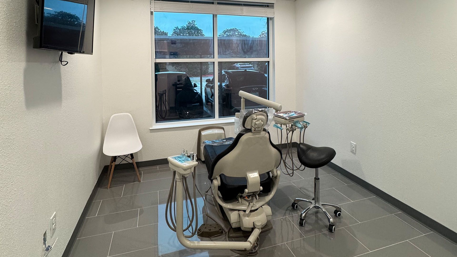 A dental office with a dental chair and a television on the wall.