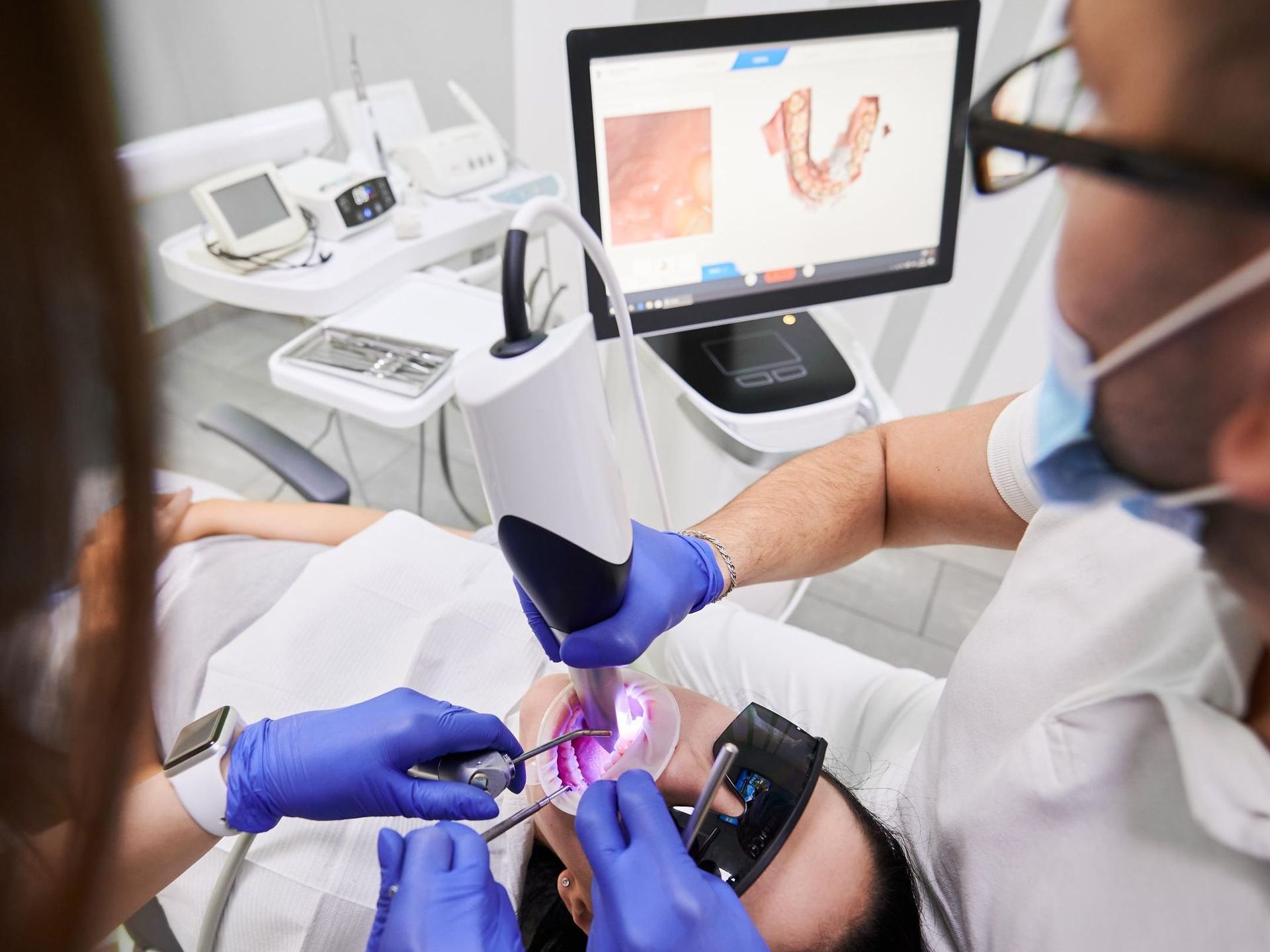 A little boy is sitting in a dental chair getting his teeth examined by a dentist.