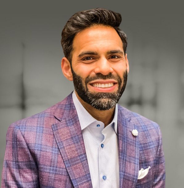 Dr. Oman Yusuf wearing a purple suit and smiling.