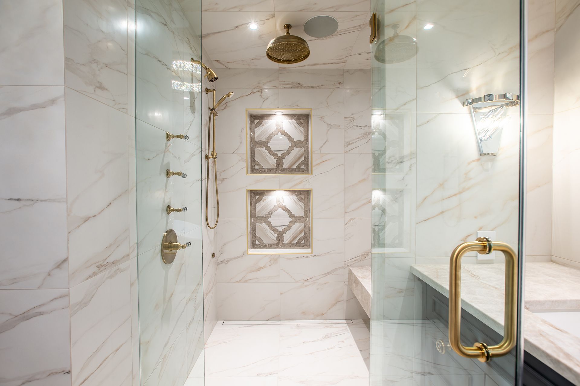 Luxurious marble shower with gold fixtures and glass doors.