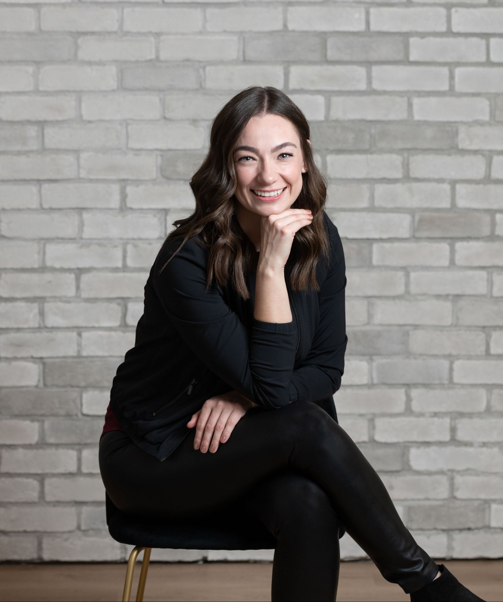 a woman is sitting on a chair in front of a brick wall .