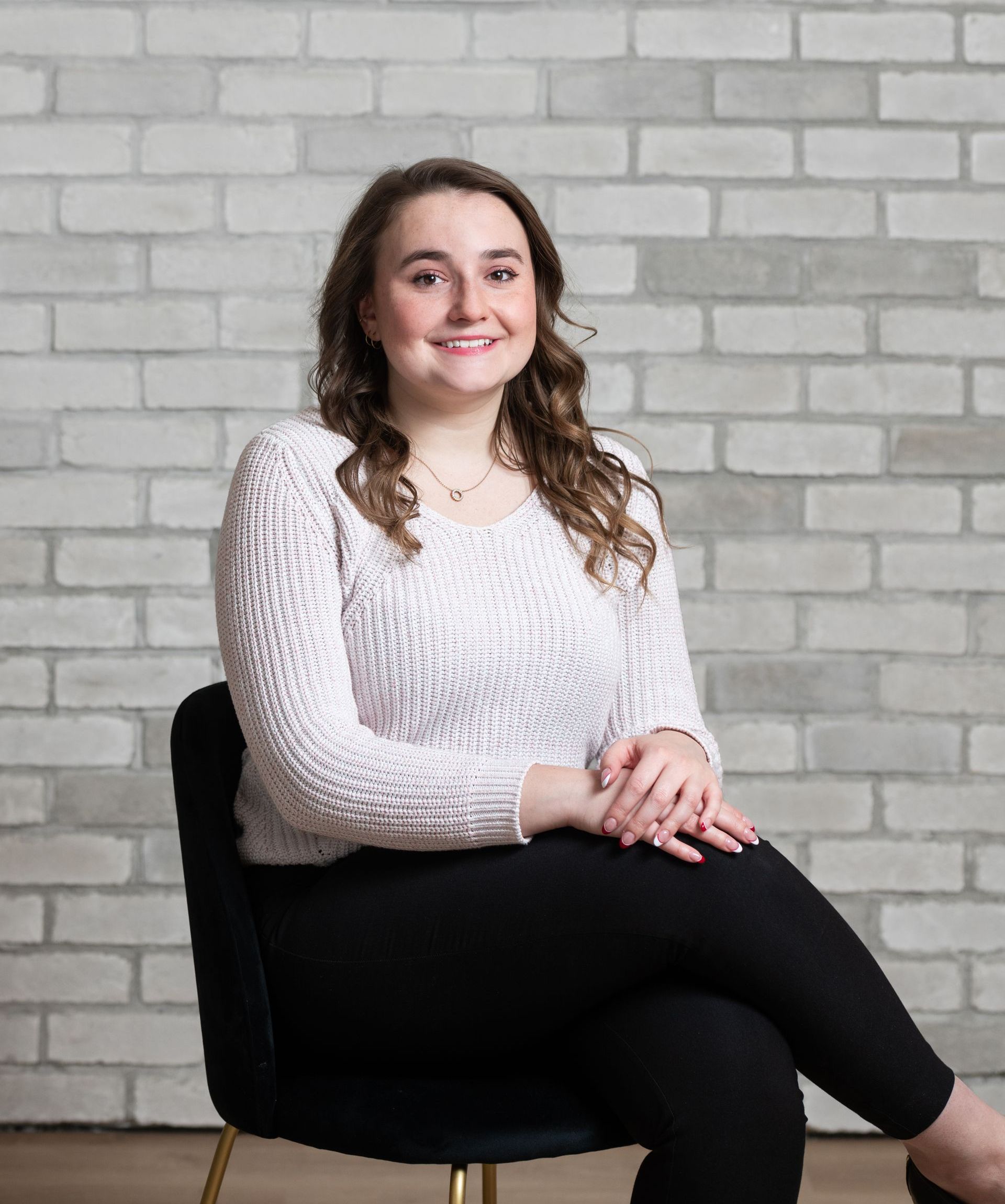 a woman is sitting in a chair in front of a brick wall .