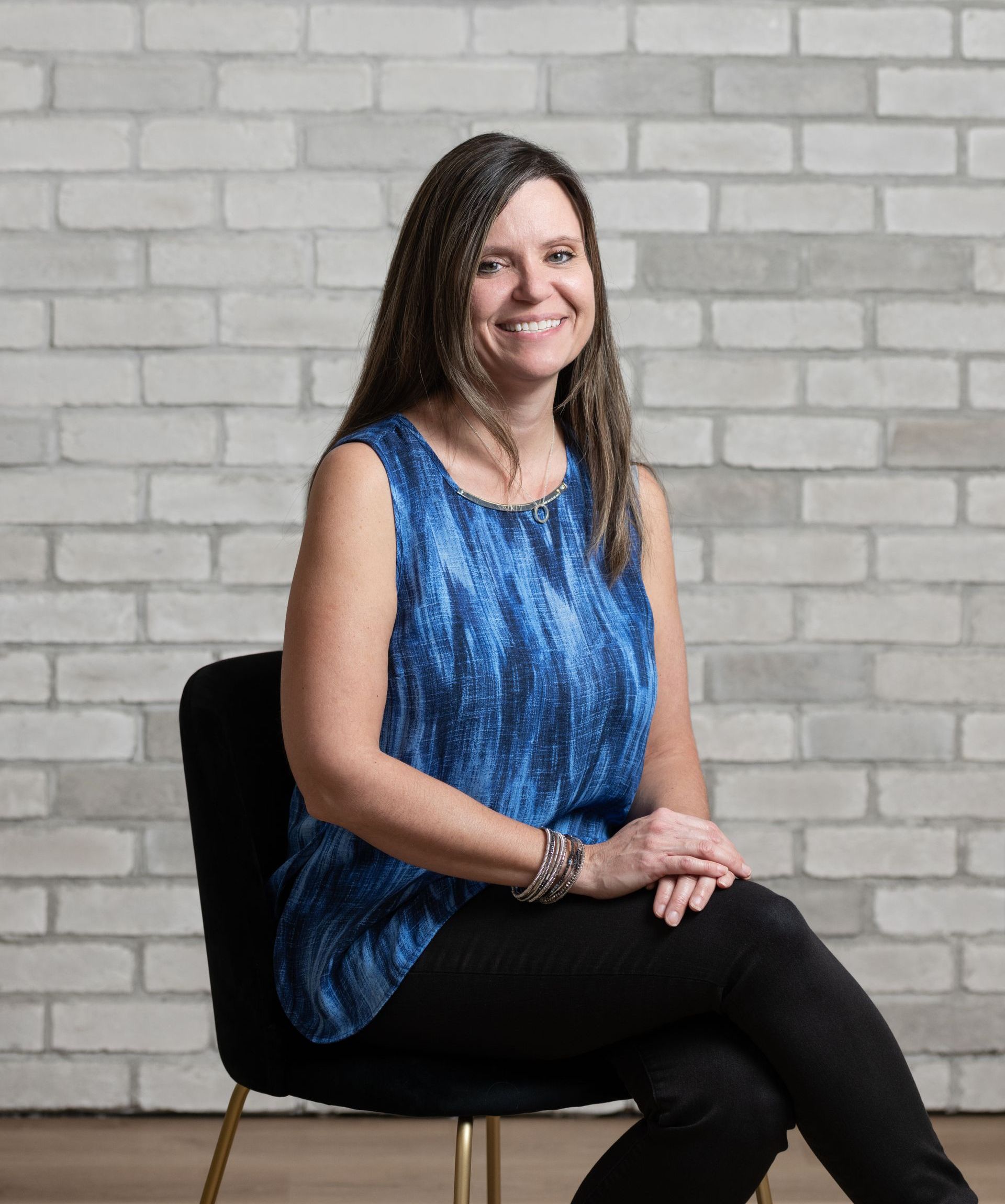 a woman is sitting in a chair in front of a brick wall .