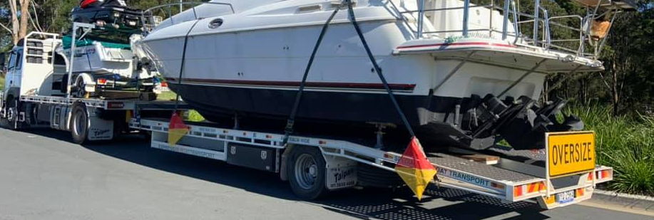 A boat is being towed down a road by a tow truck.