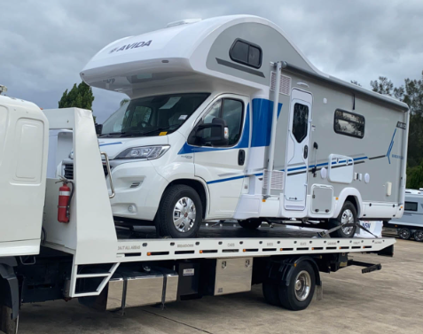 A rv is being towed by a tow truck.