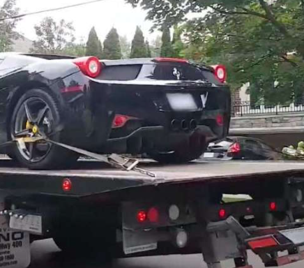A black sports car is being towed by a tow truck.