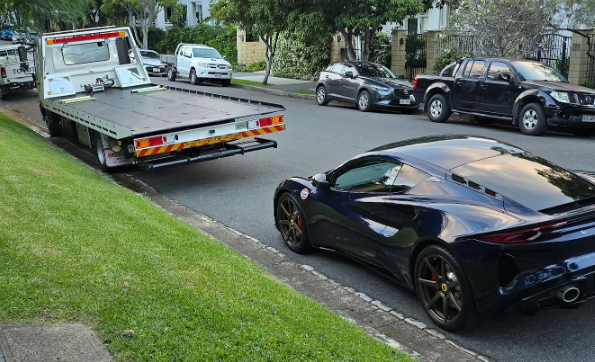 A black sports car is being towed by a tow truck.