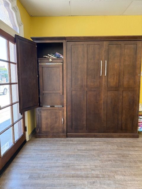 Wooden wardrobe and cabinet in a room with yellow walls and a sliding glass door.