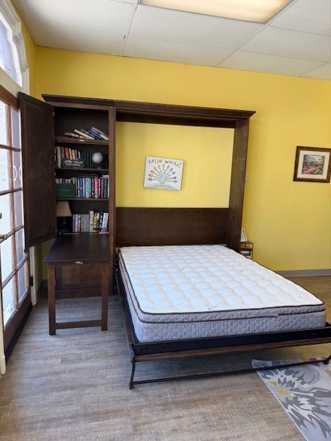 Bedroom with a dark wood bed, built-in shelves, yellow walls, and a ceiling light.
