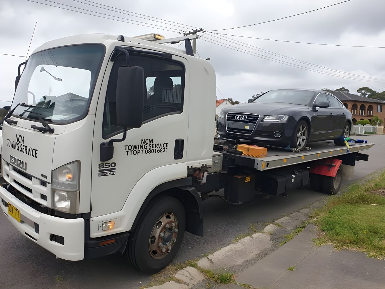 Tow Truck With a Car on the Back is Parked on the Side of the Road — NCM Towing Newcastle In Kurri Kurri, NSW