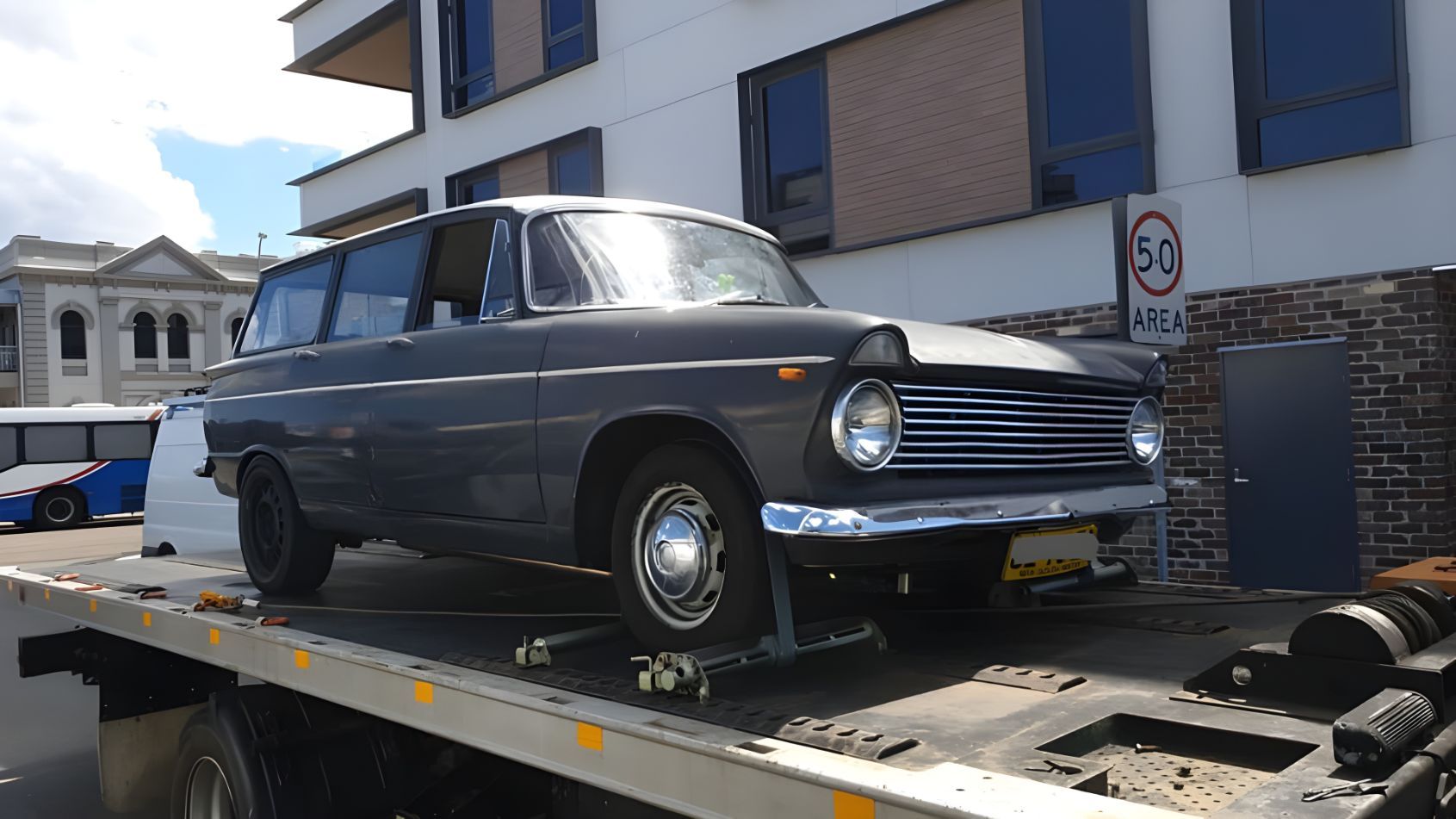 Old Car is Sitting on Top of a Tow Truck — NCM Towing Newcastle In Lake Macquarie, NSW