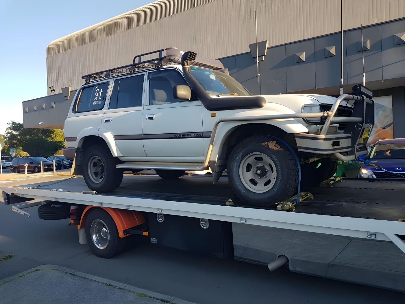 White Suv is Sitting on Top of a Tow Truck — NCM Towing Newcastle In Broadmeadow, NSW