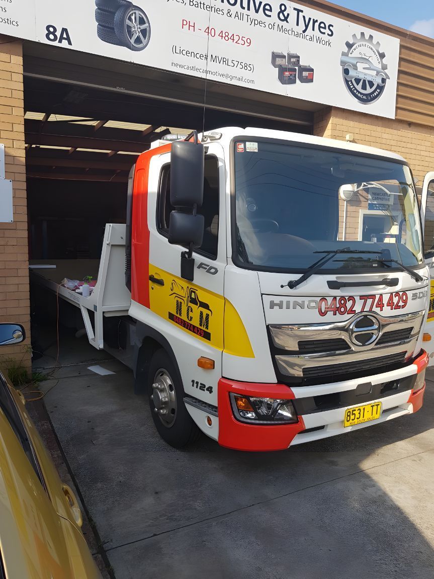 White and Red Tow Truck is Parked in Front of a Garage — NCM Towing Newcastle In Broadmeadow, NSW