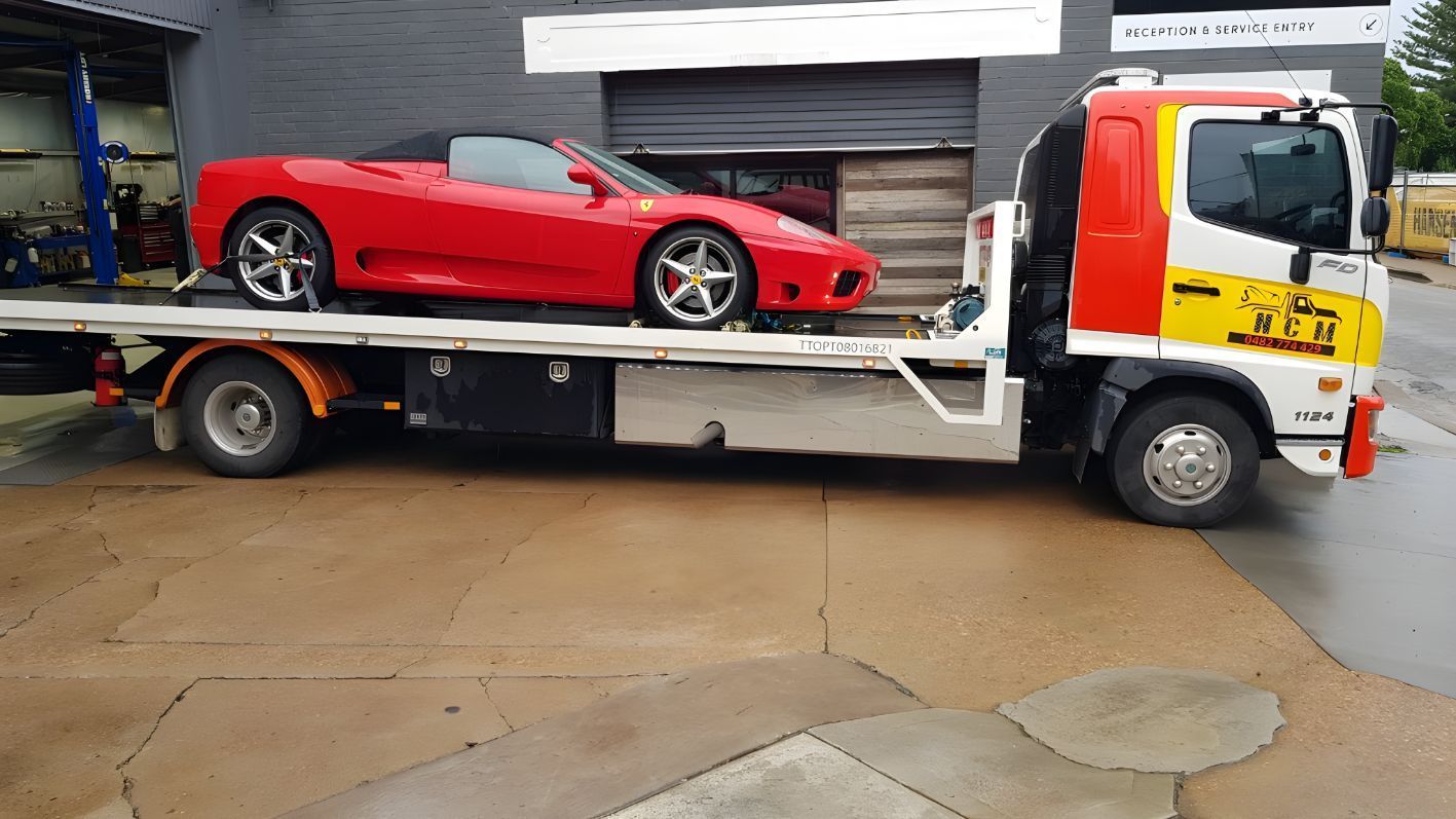 Red Sports Car is Being Towed by a Tow Truck — NCM Towing Newcastle In Karuah, NSW