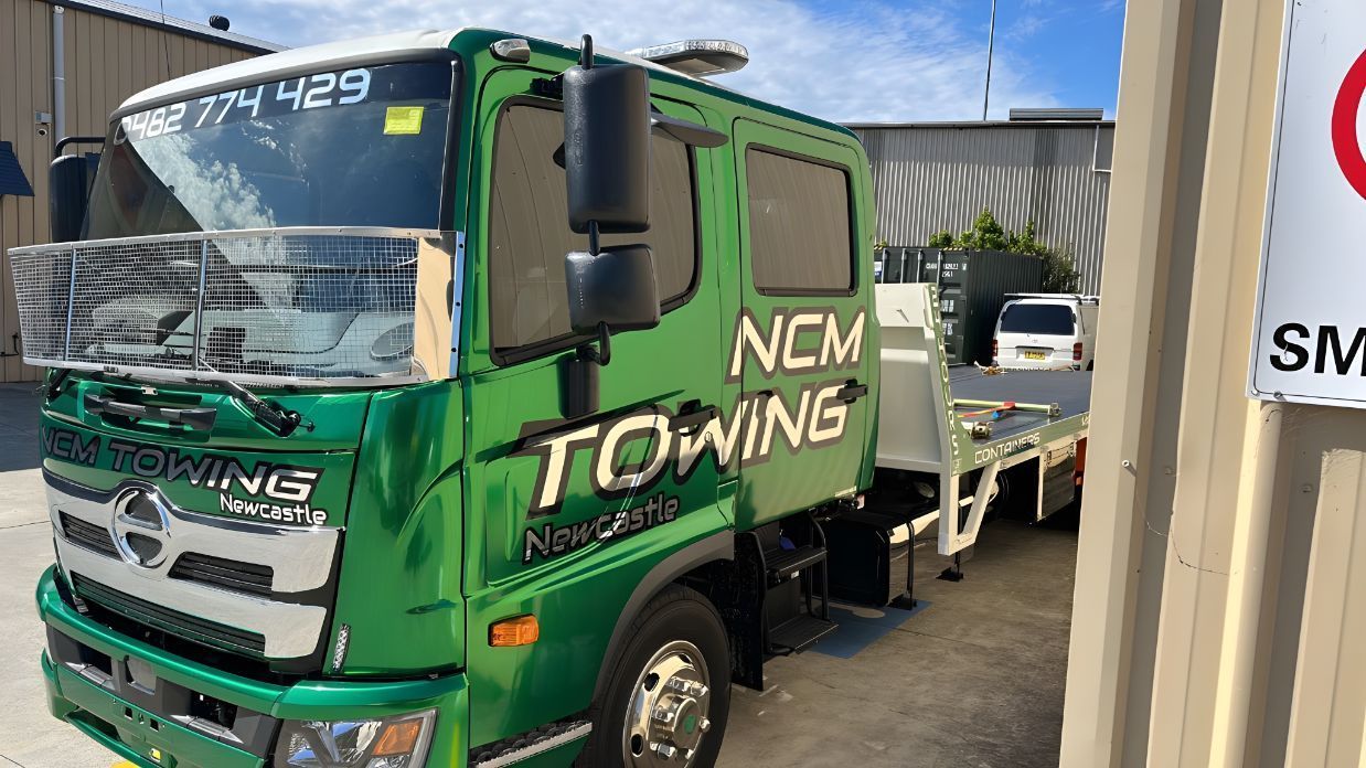 Green Towing Truck is Parked Next to a Sign — NCM Towing Newcastle In Karuah, NSW