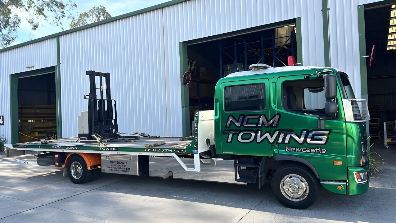 Green Towing Truck With a Forklift on the Back is Parked in Front of a Building — NCM Towing Newcastle In Broadmeadow, NSW