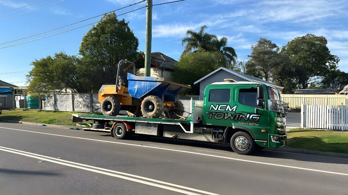 Tow Truck With a Dump Truck on the Back is Parked on the Side of the Road — NCM Towing Newcastle In Stockton, NSW