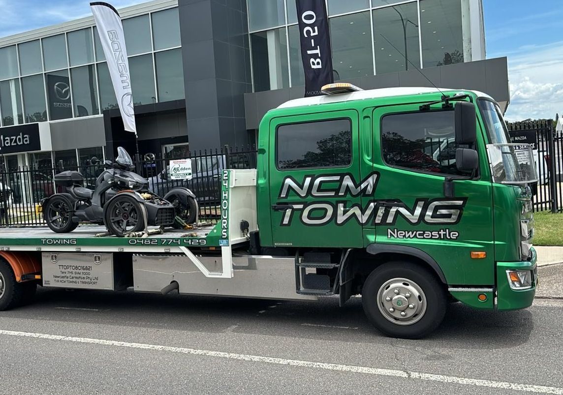 Tow Truck With a Motorcycle on the Back is Parked on the Side of the Road — NCM Towing Newcastle In Broadmeadow, NSW