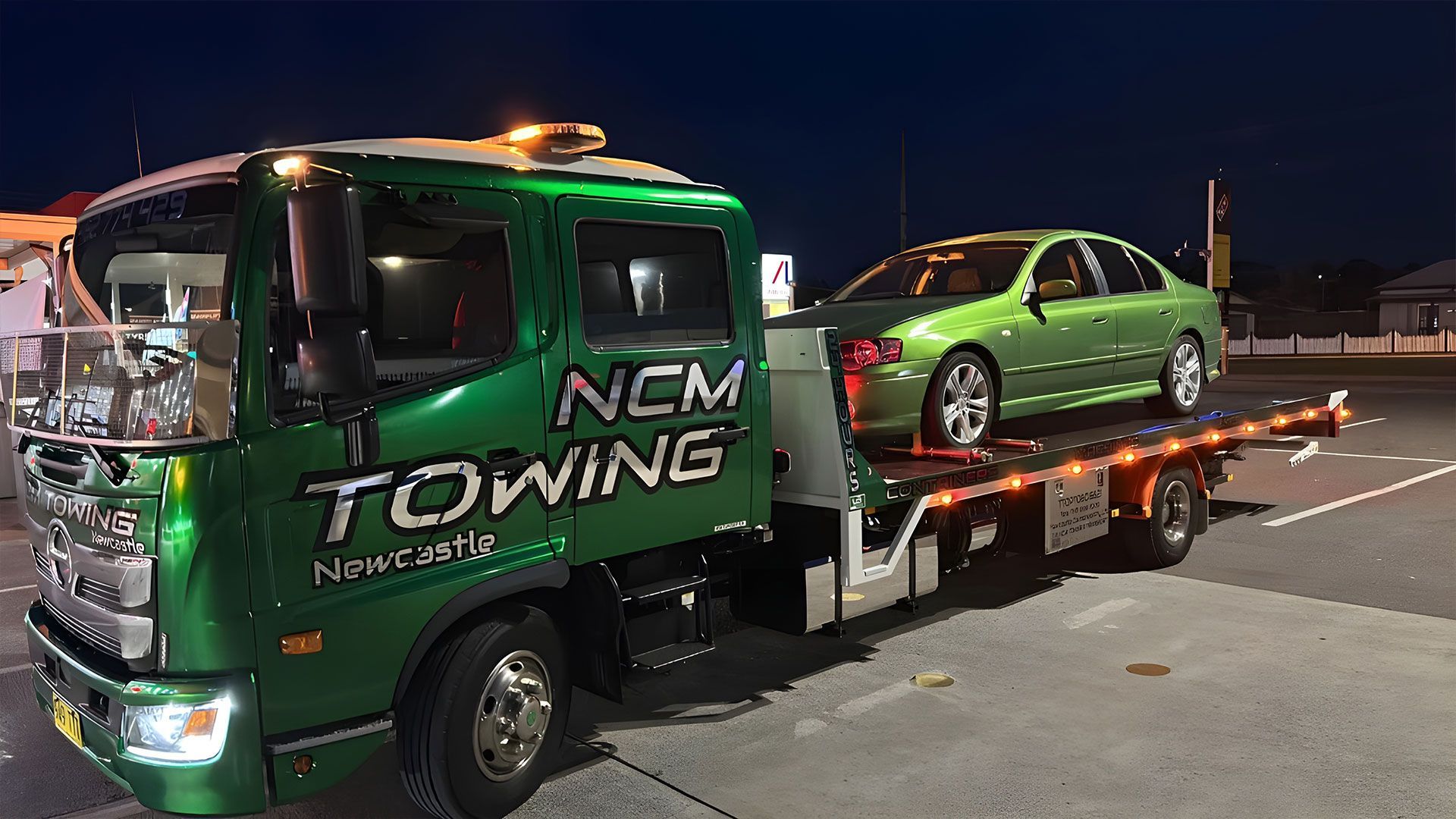 Green Car is Sitting on Top of a Tow Truck — NCM Towing Newcastle In Broadmeadow, NSW
