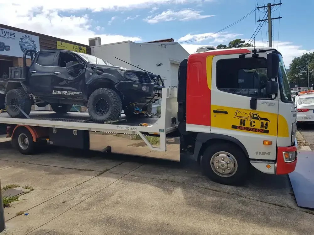 Tow Truck is Carrying a Wrecked Car on Its Flatbed — NCM Towing Newcastle In Maitland, NSW