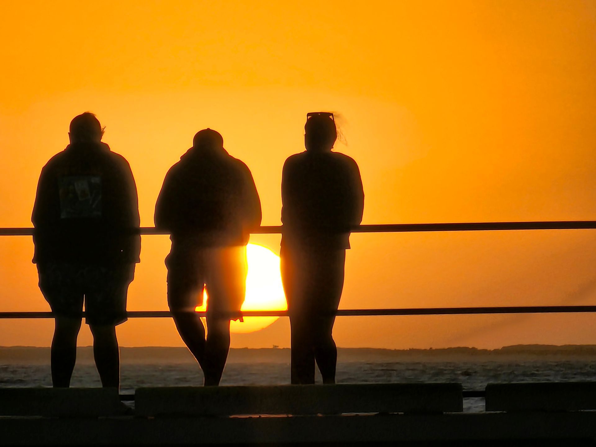 Three Silhouetted People Stand by a Railing — Coastal Vibez In Ourimbah, NSW