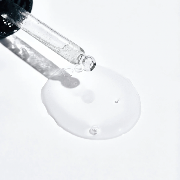Eine Nahaufnahme eines Flüssigkeitstropfens, der aus einer Pipette kommt.