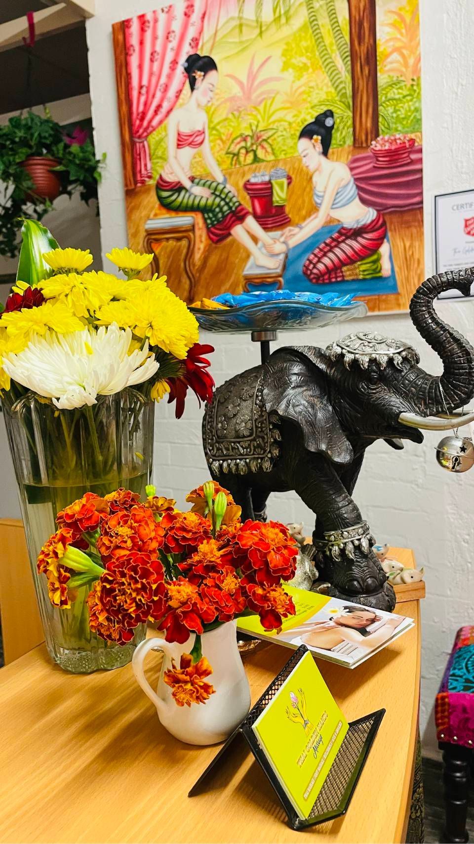 Flower arrangement display with elephant decor and colorful artwork in the background