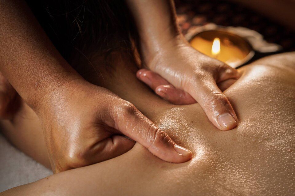 Hands giving a back massage with warm candlelight nearby