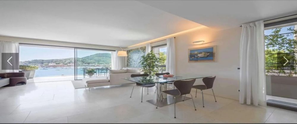 Cucina stretta con finestra affacciata sul mare e lungo bagno moderno con vasca e pavimento in legno.