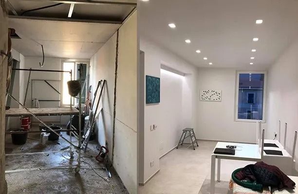Vista divisa tra un cantiere e una luminosa stanza ristrutturata con pareti bianche e faretti a incasso.