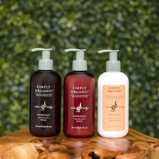 Three bottles of simply organic lotion are sitting on a wooden stump.