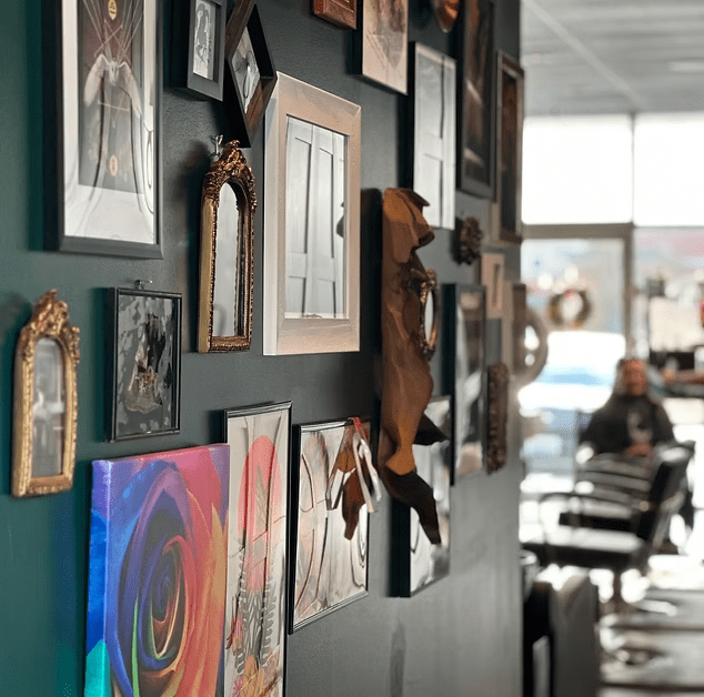 A wall filled with lots of pictures and paintings in a salon.