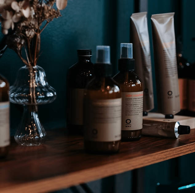 A wooden table topped with bottles of hair products and a vase of flowers.