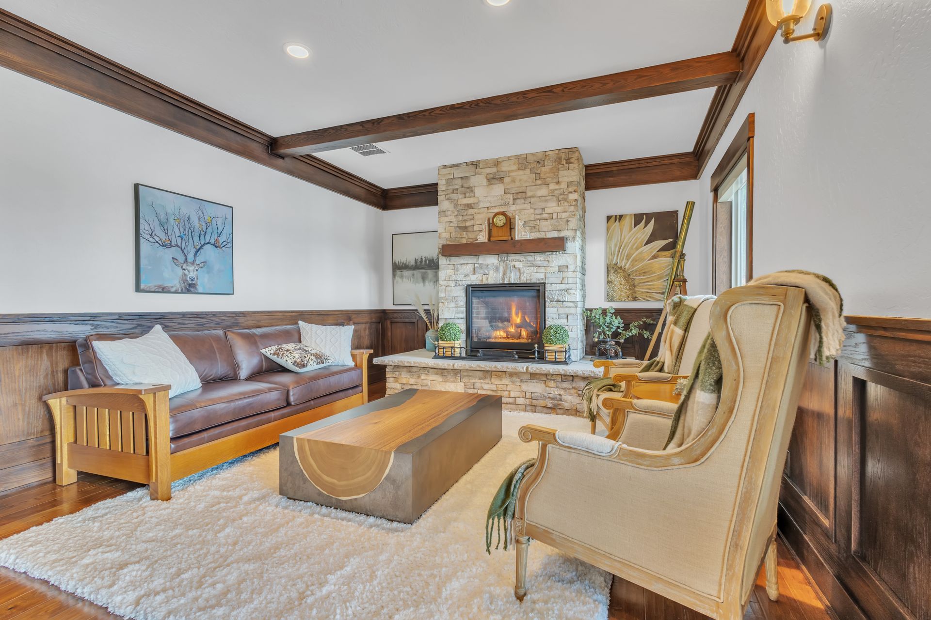 Cozy living room with fireplace, brown leather couch, and two armchairs on a white rug.